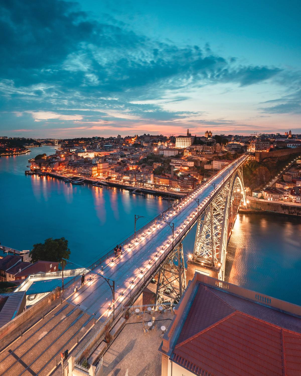 O Porto ao anoitecer, com a ponte D. Luís I e a Ribeira iluminadas sobre o Douro